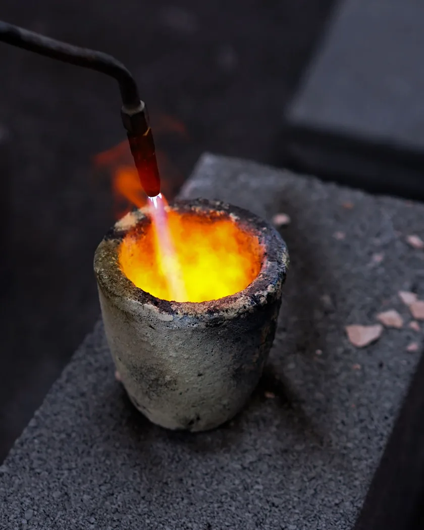 Primer plano de un crisol al rojo vivo durante la fusión del metal en un taller